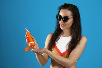 Young woman applying sun protection cream on dark blue background