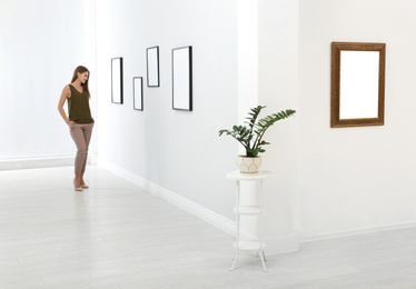 Photo of Young woman viewing exposition in modern art gallery