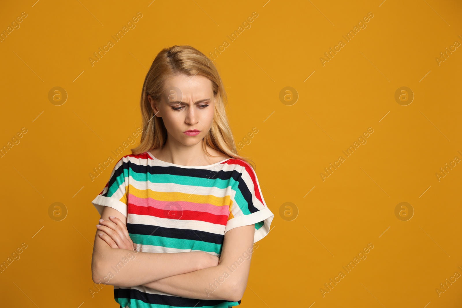 Photo of Angry young woman on yellow background, space for text. Hate concept
