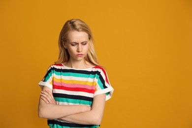 Angry young woman on yellow background, space for text. Hate concept