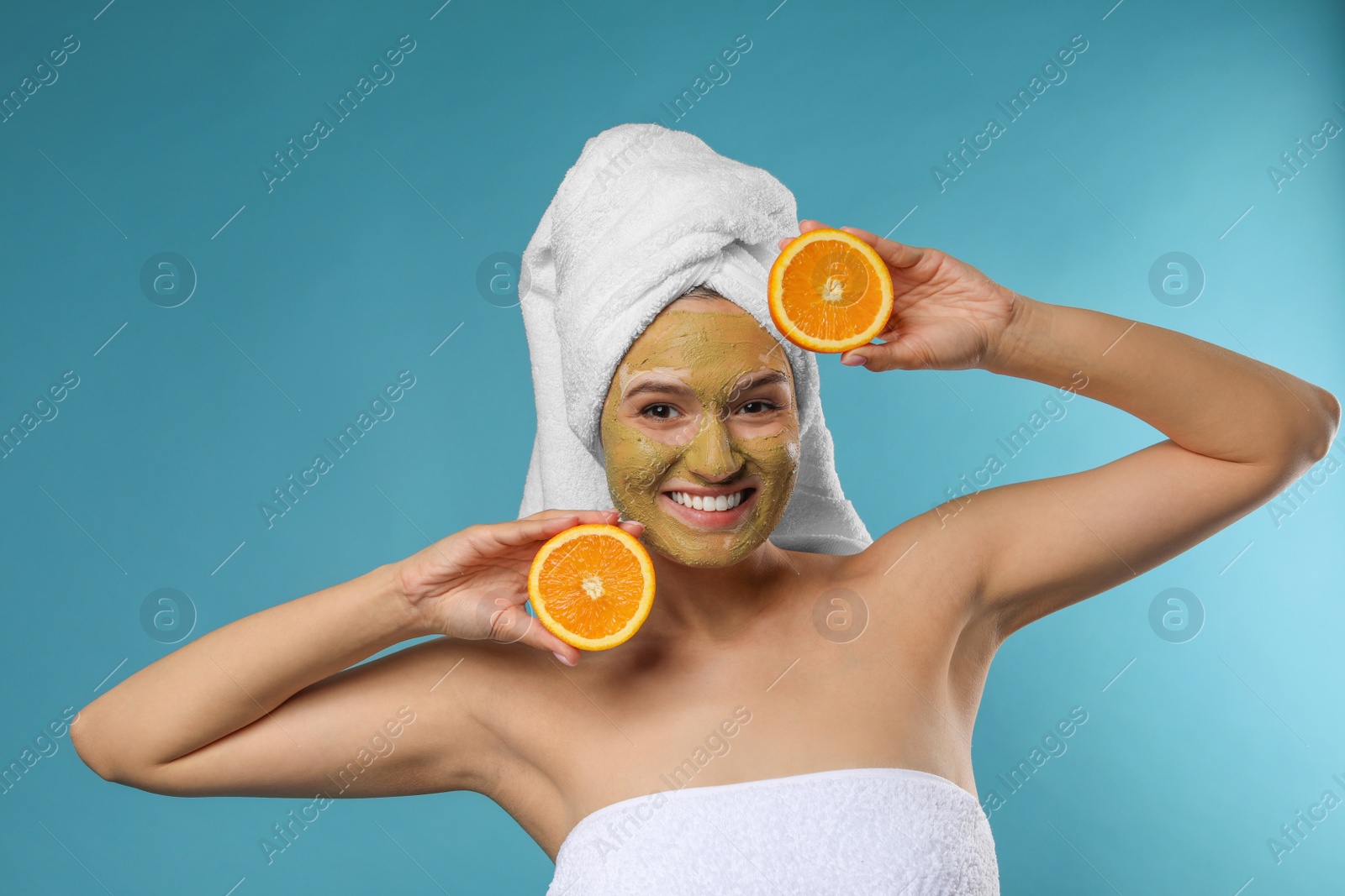 Photo of Beautiful woman with mask on face and cut orange against color background