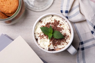 Cup of delicious hot chocolate with whipped cream and mint on white wooden table, flat lay