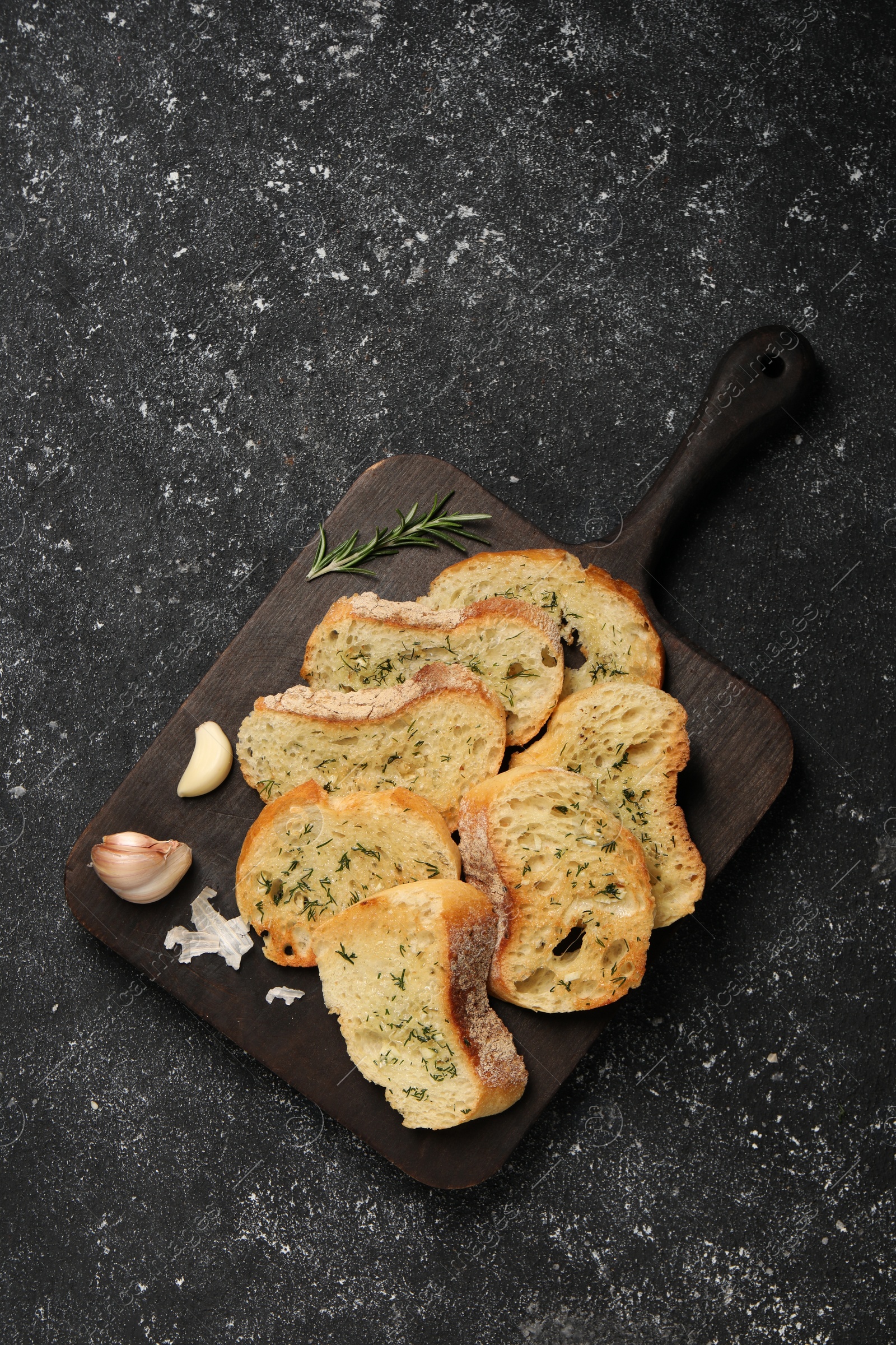 Photo of Tasty baguette with garlic, dill and rosemary on grey textured table, top view