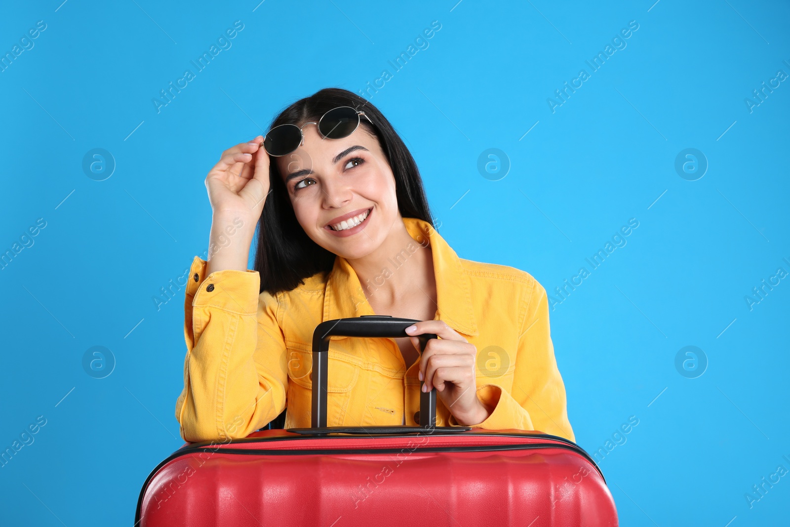 Photo of Beautiful woman with suitcase for summer trip on blue background. Vacation travel