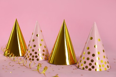 Photo of Colorful party hats and confetti on pink background