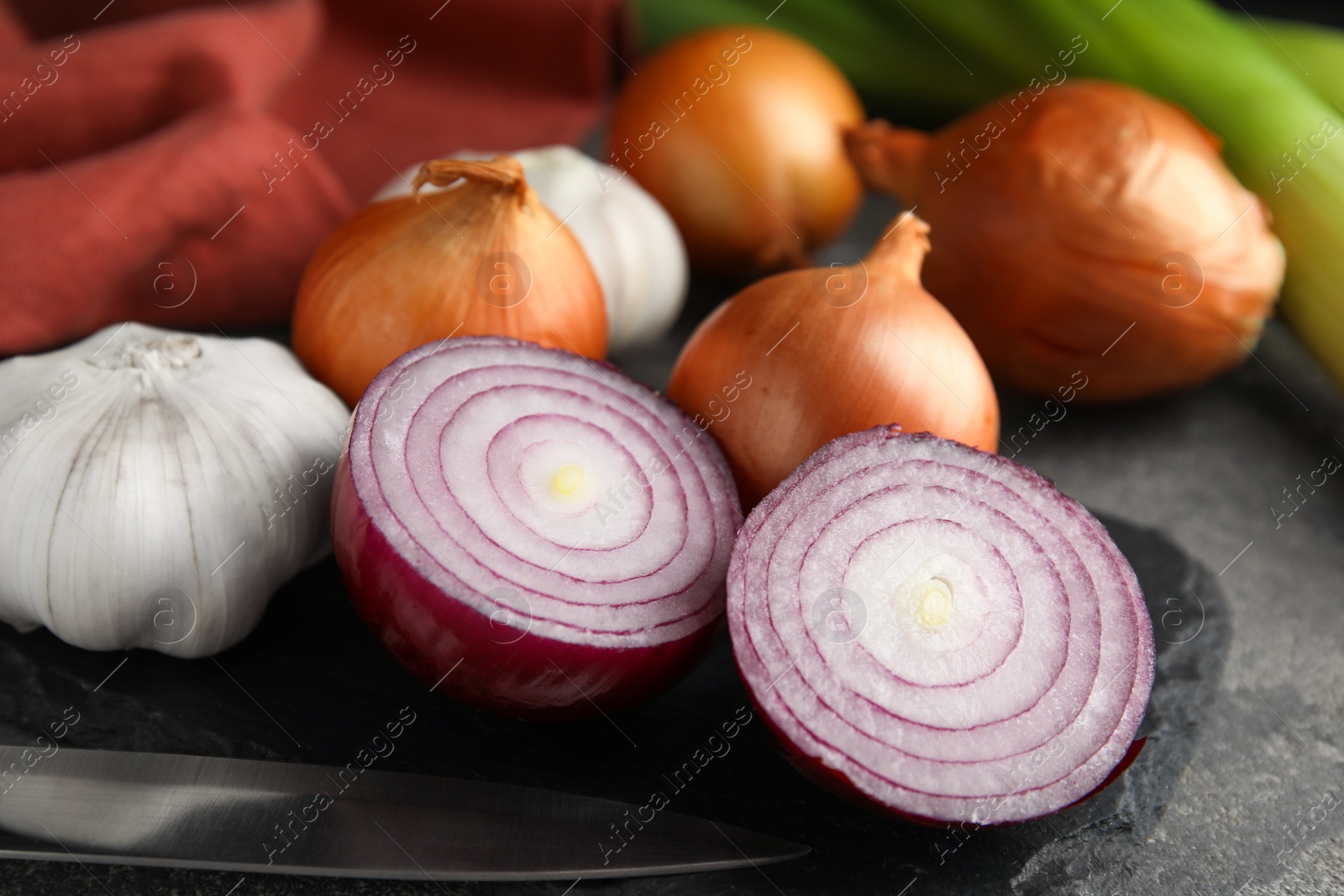 Photo of Fresh whole and cut onions, leek, garlic on grey table, closeup