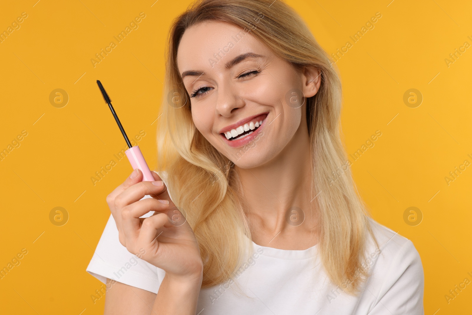 Photo of Beautiful woman with mascara on orange background
