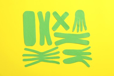 Different kinesio tape pieces on yellow background, flat lay