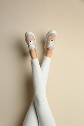 Woman wearing shoes on beige background, closeup