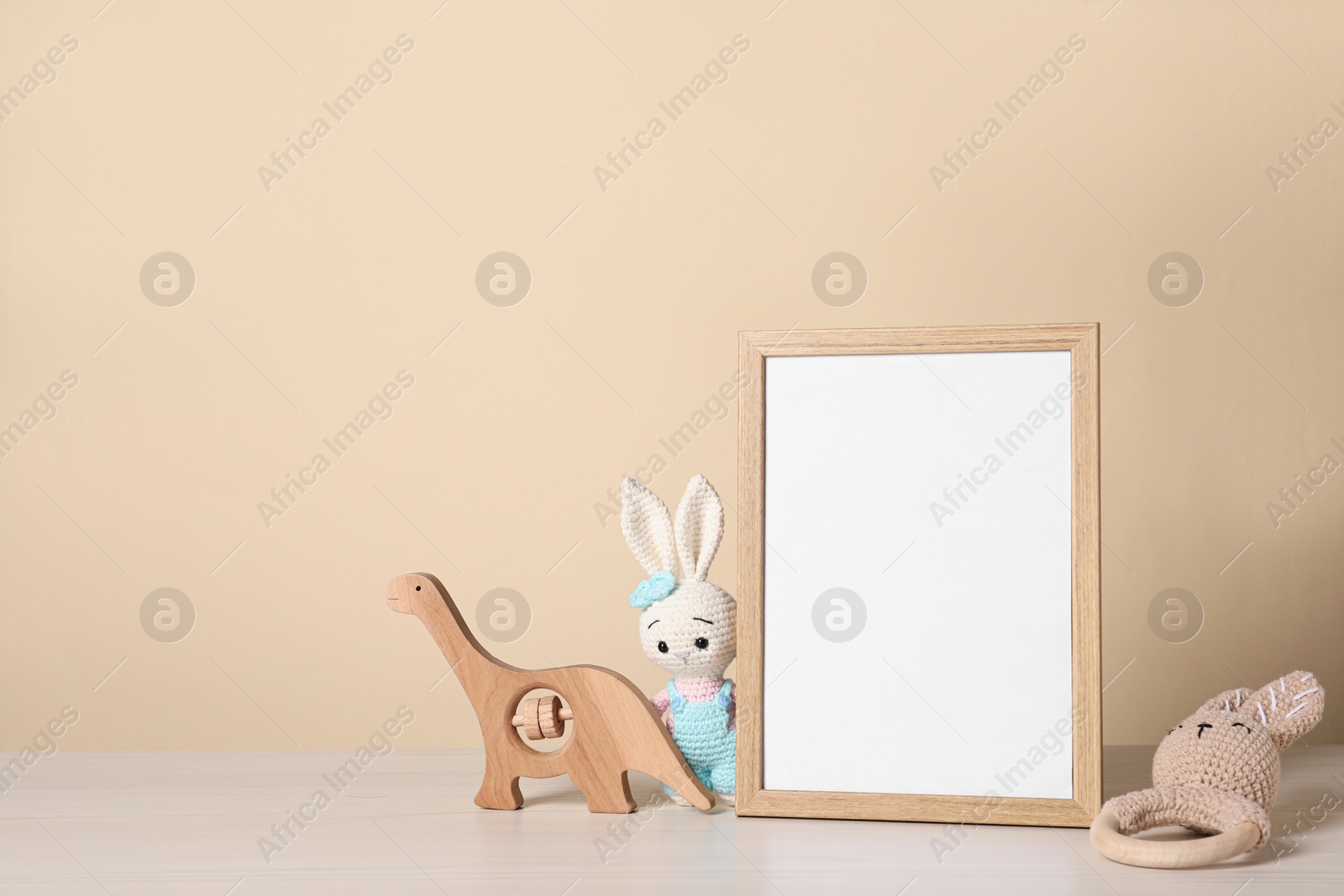 Photo of Empty square frame and different toys on white table, space for text