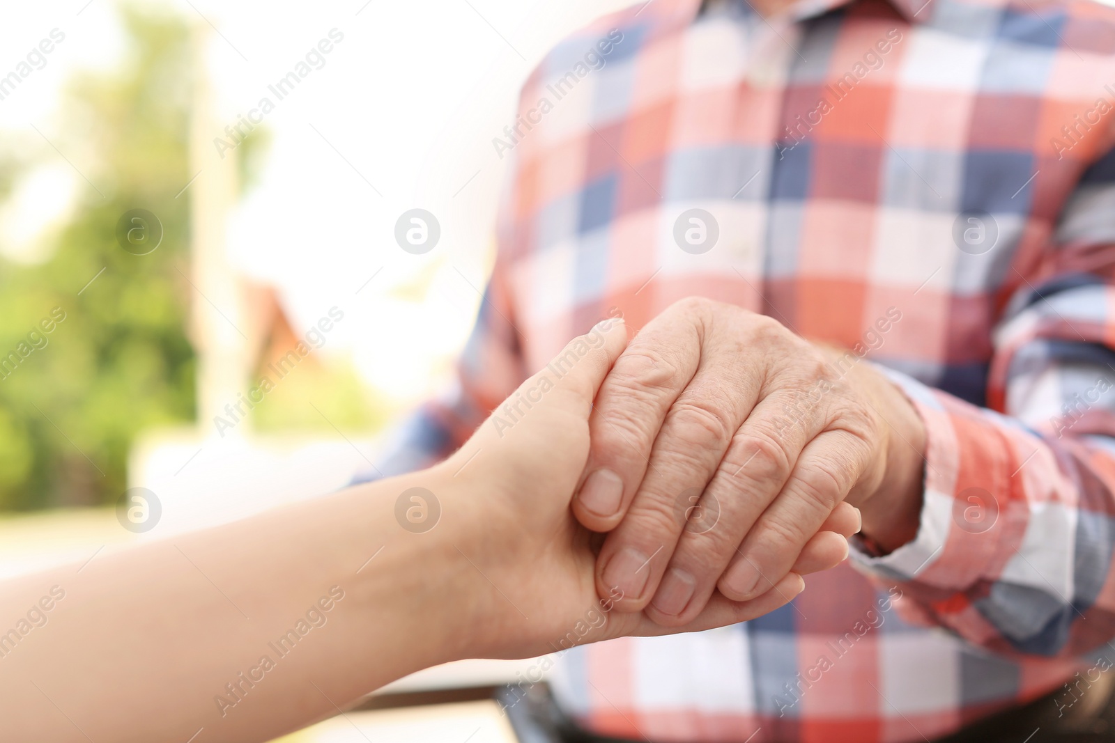 Photo of Helping hands on blurred background, closeup. Elderly care concept