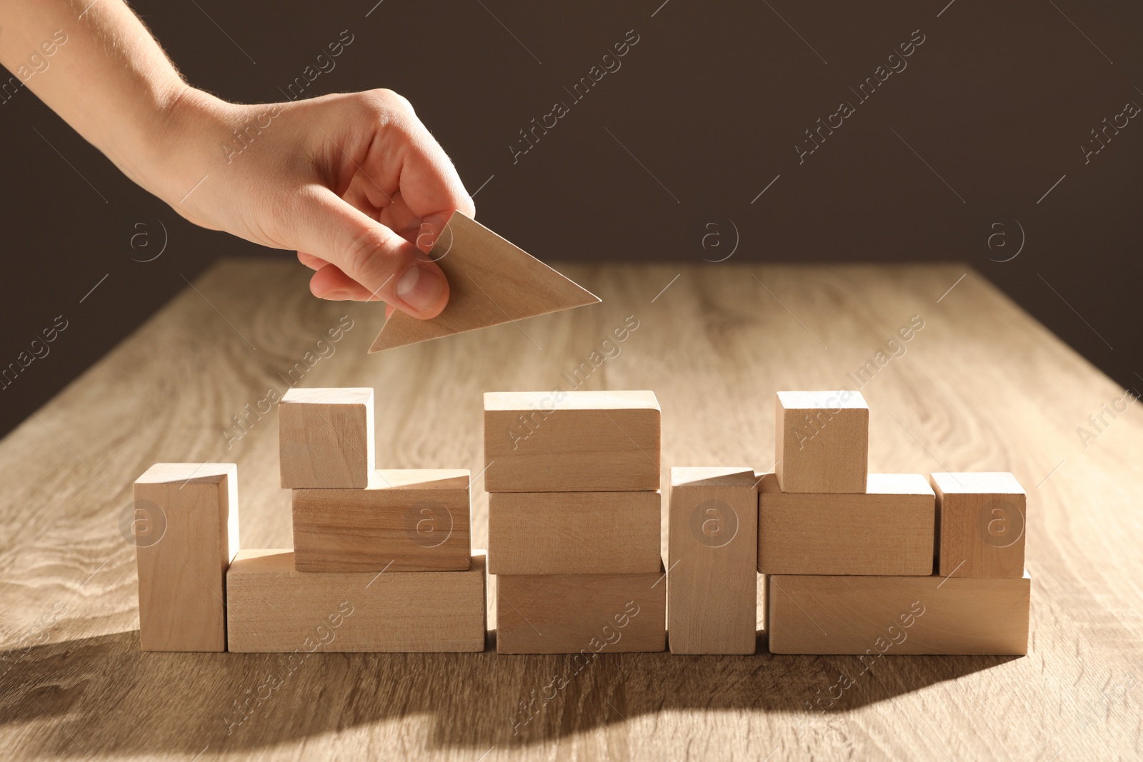 Photo of Woman constructing with wooden building blocks, closeup. Corporate social responsibility concept