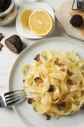 Delicious pasta with truffle slices served on white table, flat lay
