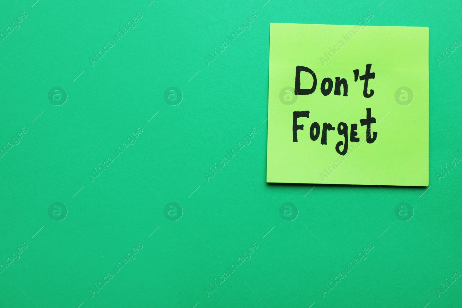 Photo of Paper note with phrase Don't Forget on green background, top view. Space for text