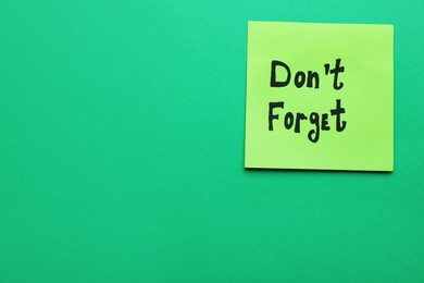Photo of Paper note with phrase Don't Forget on green background, top view. Space for text