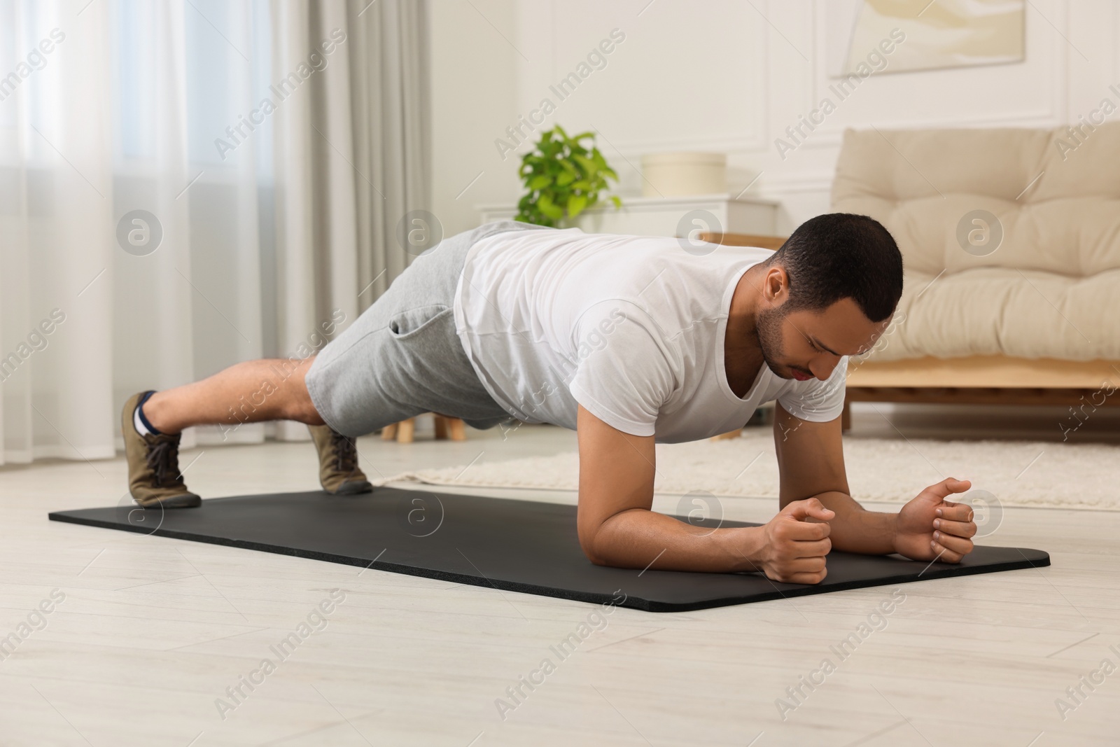 Photo of Man doing morning exercise on fitness mat at home