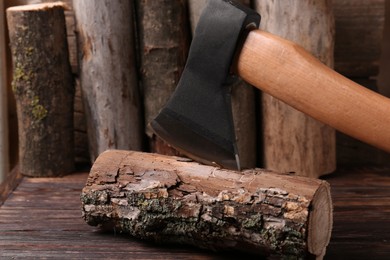 Metal axe in wooden log on table, closeup