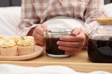 Woman with cup of hot drink in bed, closeup