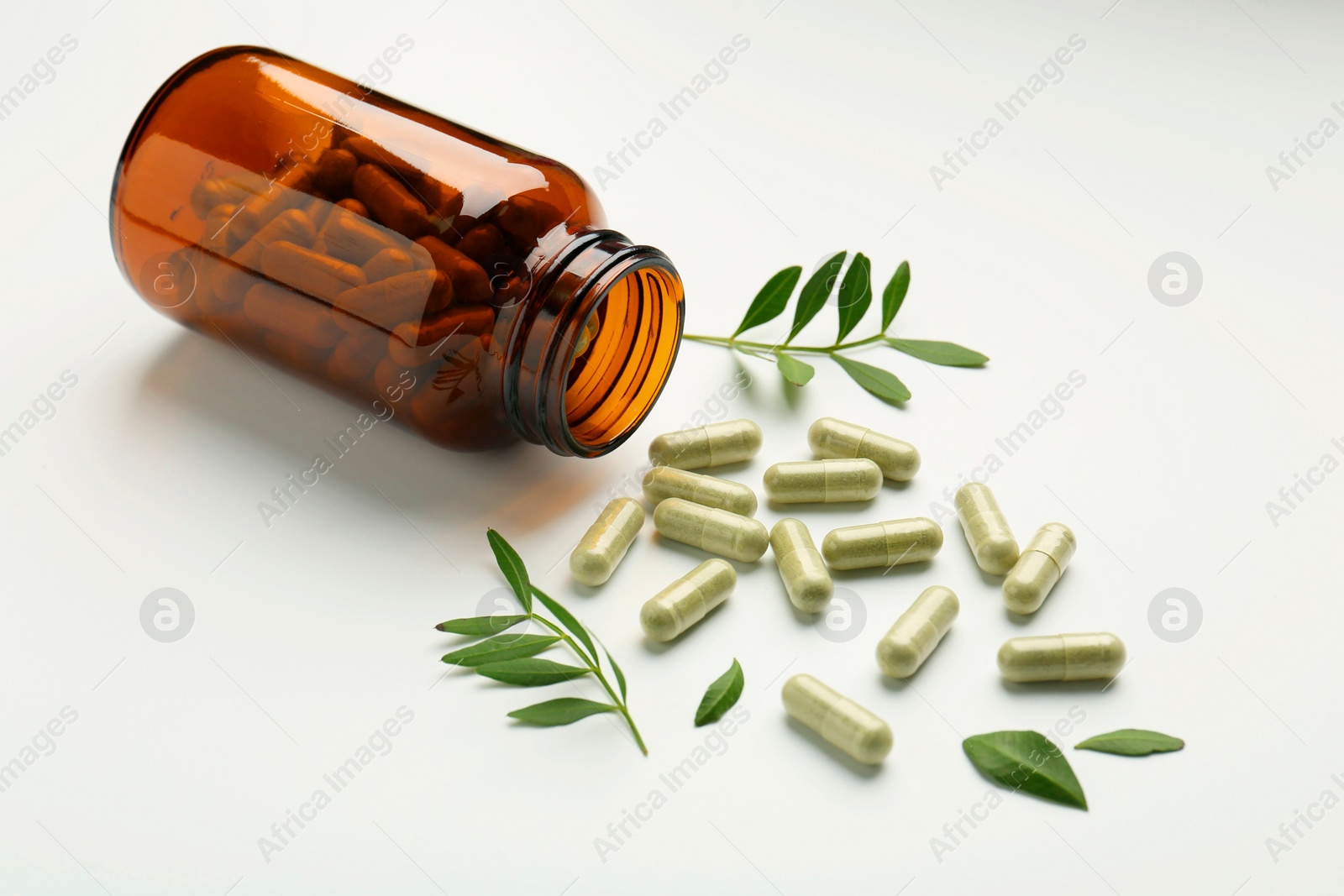 Photo of Bottle, vitamin capsules and leaves on white background