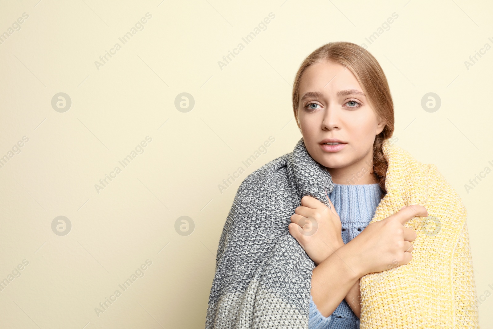 Image of Young woman wrapped in blanket suffering from fever on light background, space for text. Cold symptoms