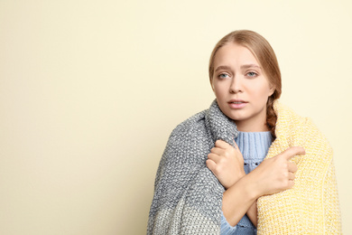 Image of Young woman wrapped in blanket suffering from fever on light background, space for text. Cold symptoms