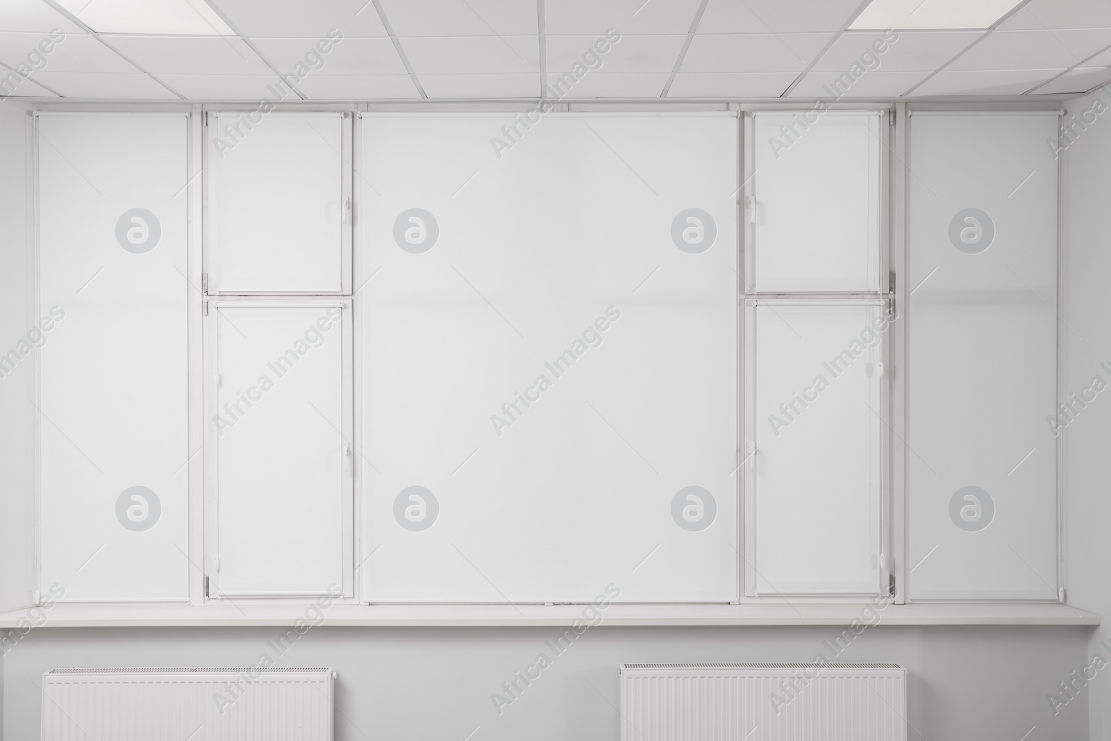 Photo of Windows covered with white roller blinds indoors