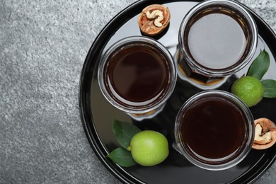 Photo of Delicious liqueur and fresh walnuts on grey table, top view. Space for text