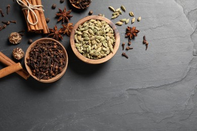 Photo of Different spices in bowls on dark gray textured table, flat lay. Space for text