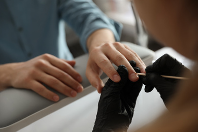 Photo of Professional manicurist working with client in beauty salon, closeup