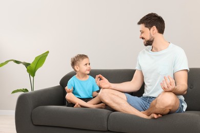 Photo of Father with son meditating together on sofa at home