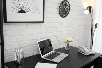 Photo of Stylish workplace interior with laptop on table