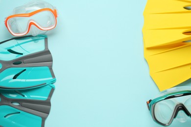 Pairs of flippers and diving masks on turquoise background, flat lay