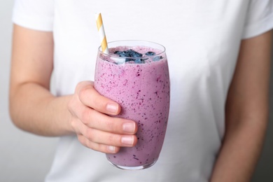 Woman holding glass of delicious blueberry smoothie, closeup