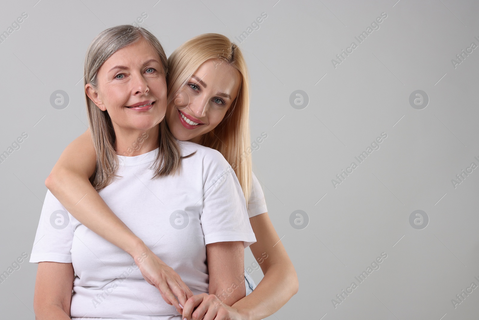 Photo of Family portrait of young woman and her mother on light grey background. Space for text