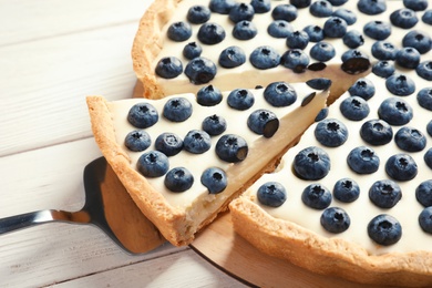 Photo of Tasty cake with blueberry and pie server on wooden table