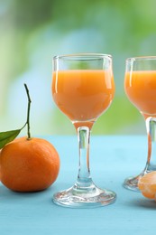 Delicious tangerine liqueur and fresh fruit on light blue wooden table