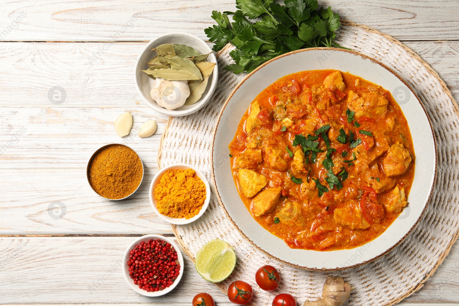 Photo of Delicious chicken curry and ingredients on wooden table, flat lay