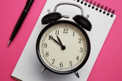 Photo of Alarm clock, pen and notebook on pink background, flat lay. Reminder concept