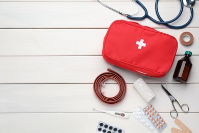 Flat lay composition with first aid kit on white wooden table, space for text