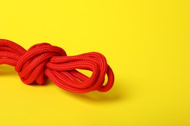 Photo of Red shoe laces tied in knot on yellow background, closeup. Space for text