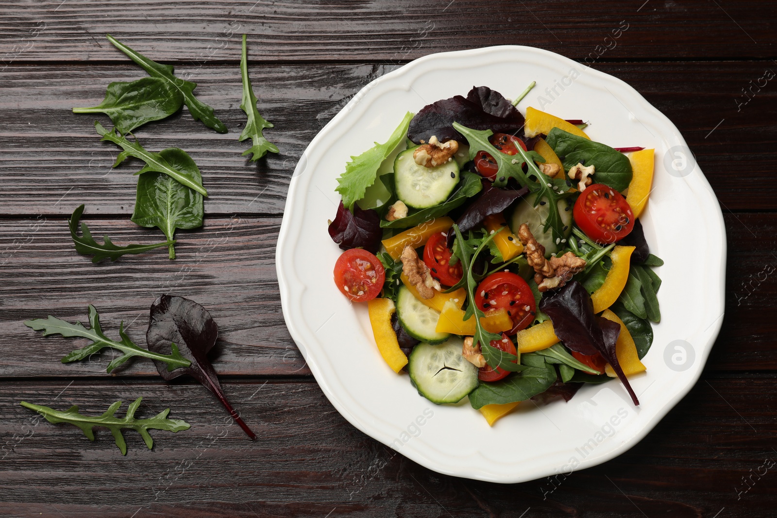 Photo of Tasty fresh vegetarian salad on dark wooden table, top view