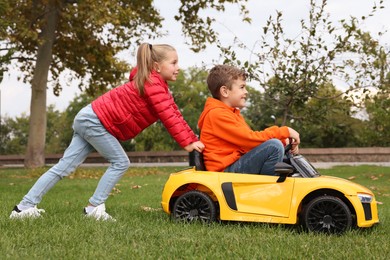 Photo of Cute girl pushing children's car with little boy in park