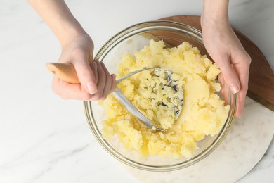 Woman making mashed potato at white marble table, top view