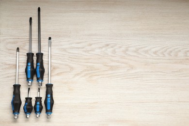 Photo of Set of screwdrivers on wooden table, flat lay. Space for text