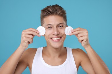 Handsome man with cotton pads on light blue background