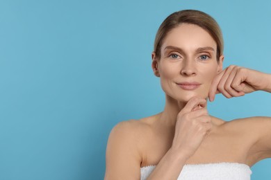 Photo of Woman massaging her face on turquoise background. Space for text