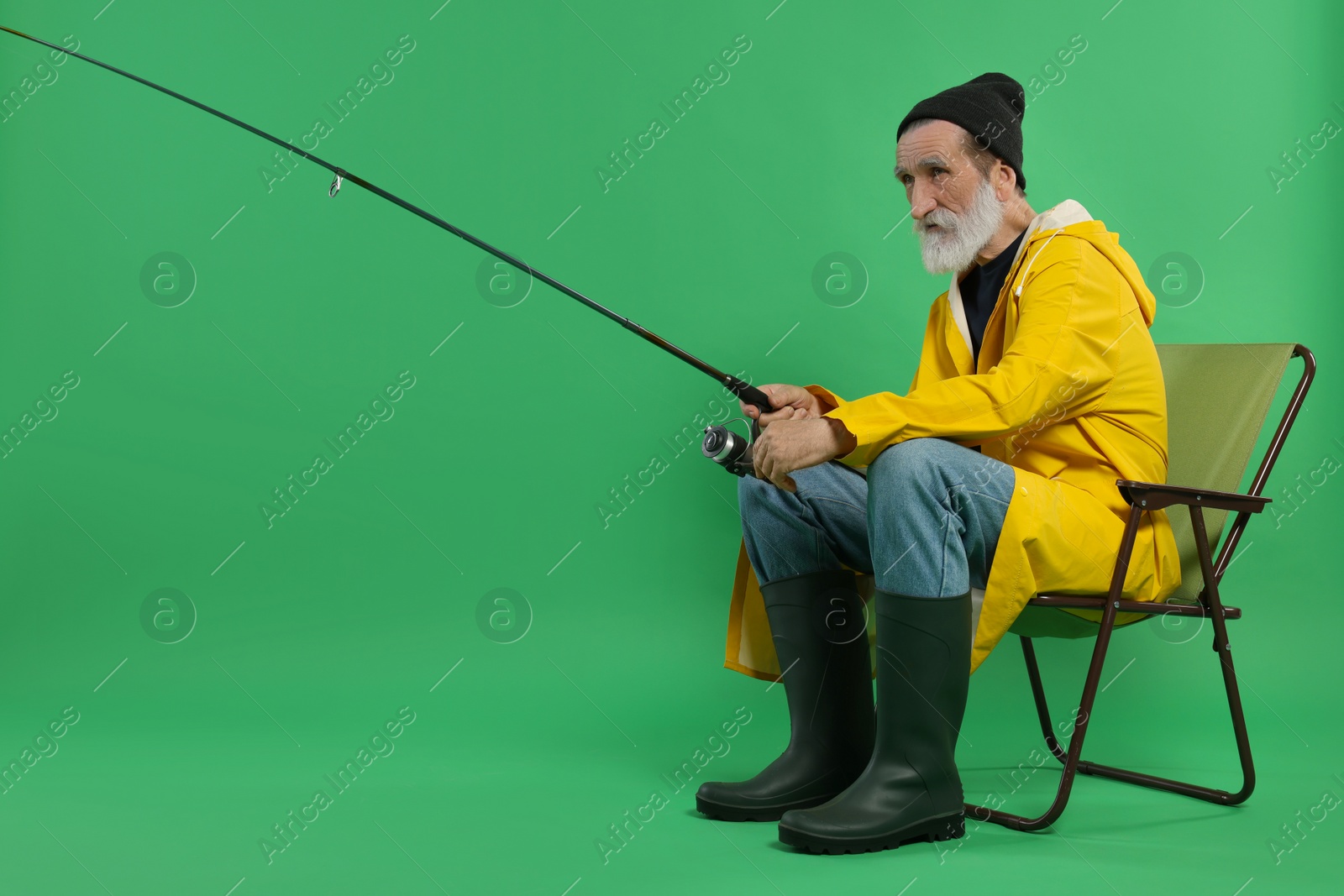 Photo of Fisherman with rod on chair against green background