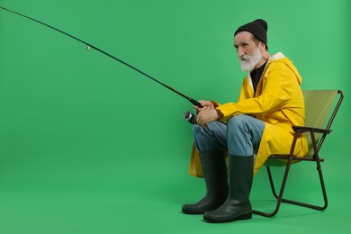 Fisherman with rod on chair against green background
