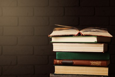 Image of Stack of old hardcover books near brick wall, space for text