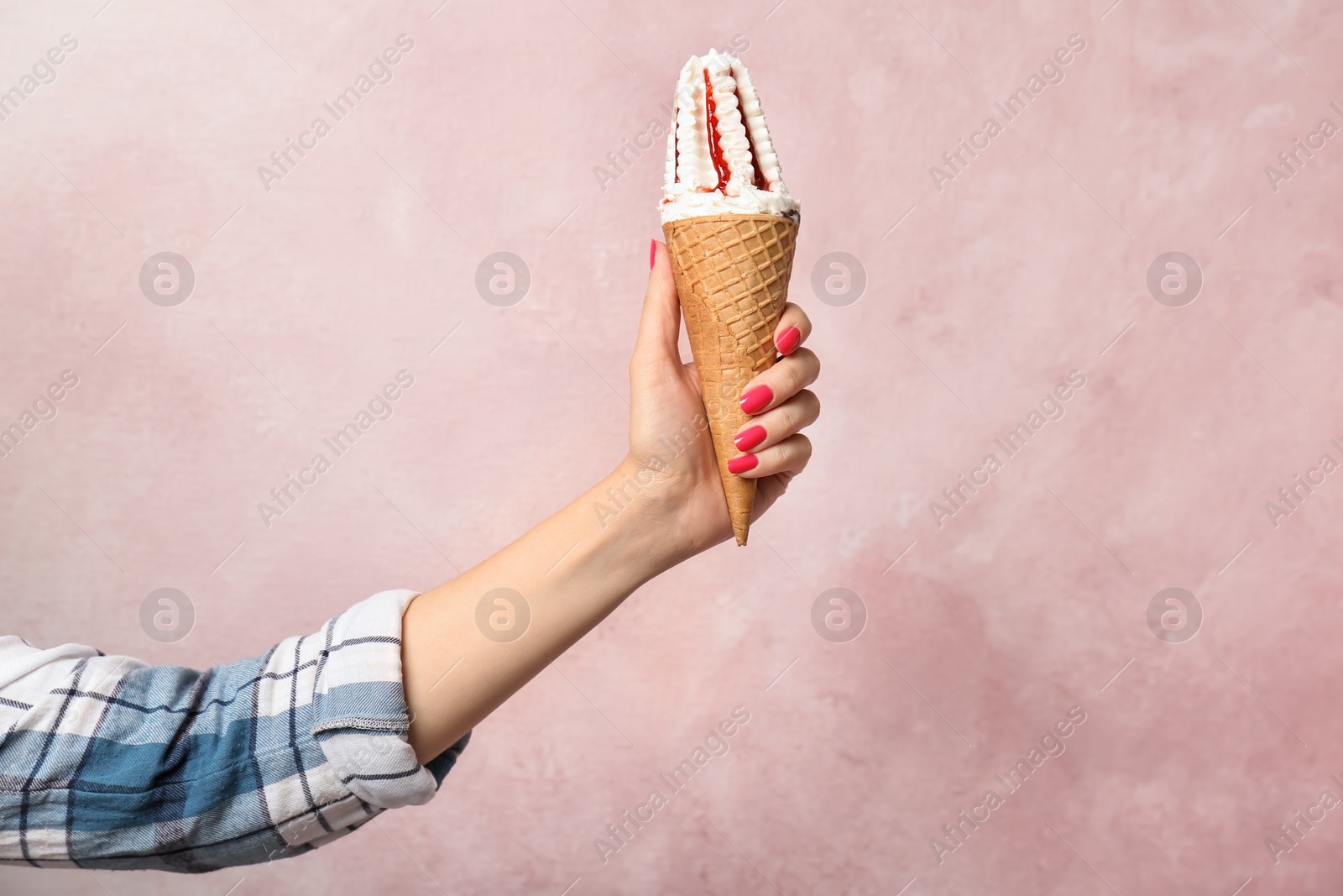 Photo of Woman holding yummy ice cream on color background. Focus on hand